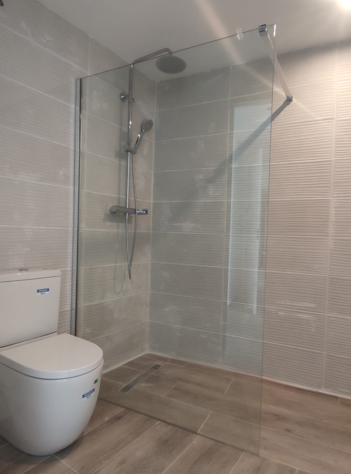 Instalación de platos de ducha con suelo porcelánico antideslizante hijita ión madera y mampara fija